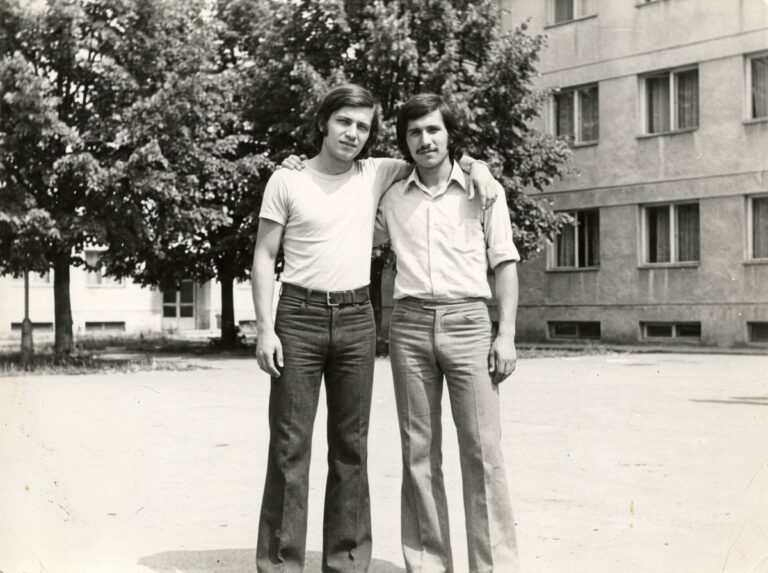 Doi tineri în fața unui bloc, anii '70 (imagine generată cu AI)