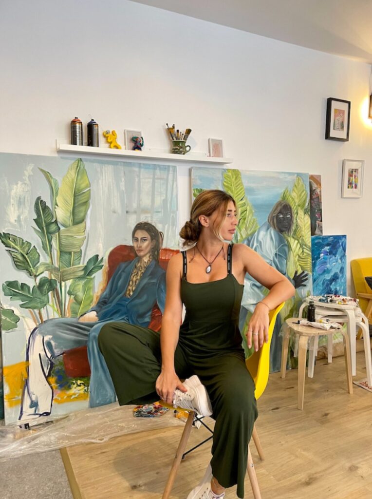 Arina Bican în atelier, în fața picturilor sale